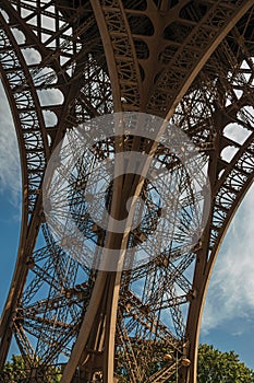View of one legÃ¢â¬â¢s iron structure of the Eiffel Tower, with blue sky and sunshine in Paris. photo